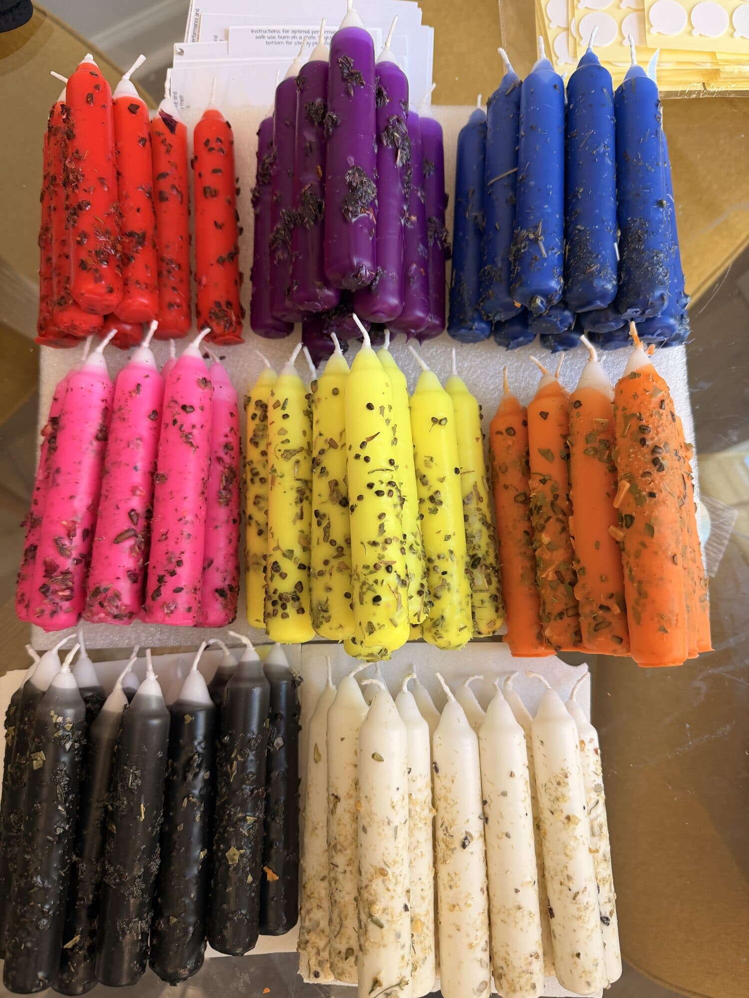 Herb-studded tapers laid out in colour groups, red, purple, blue, pink, yellow, orange, black and white