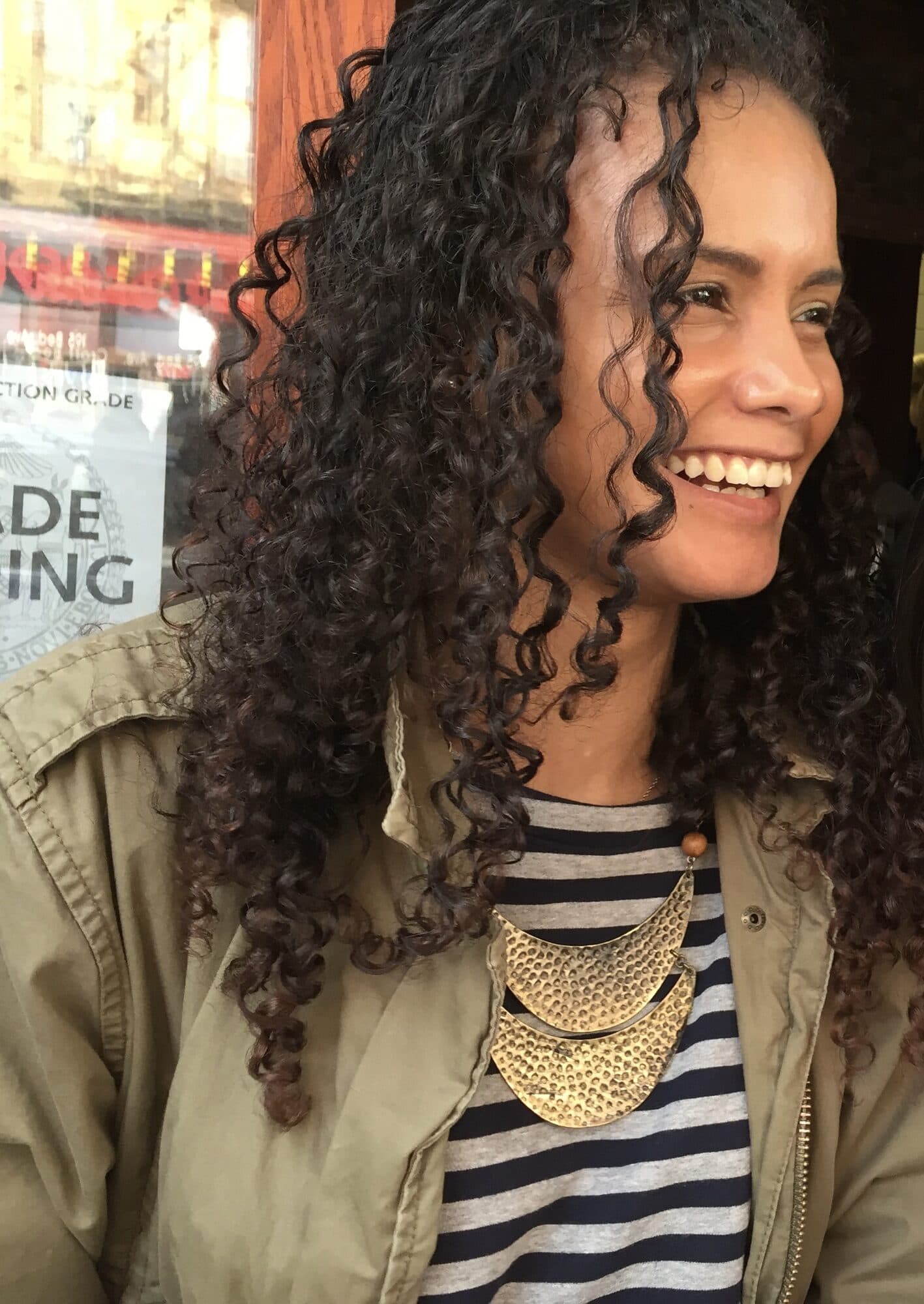 Amorette smiling, in a striped top and gold necklace