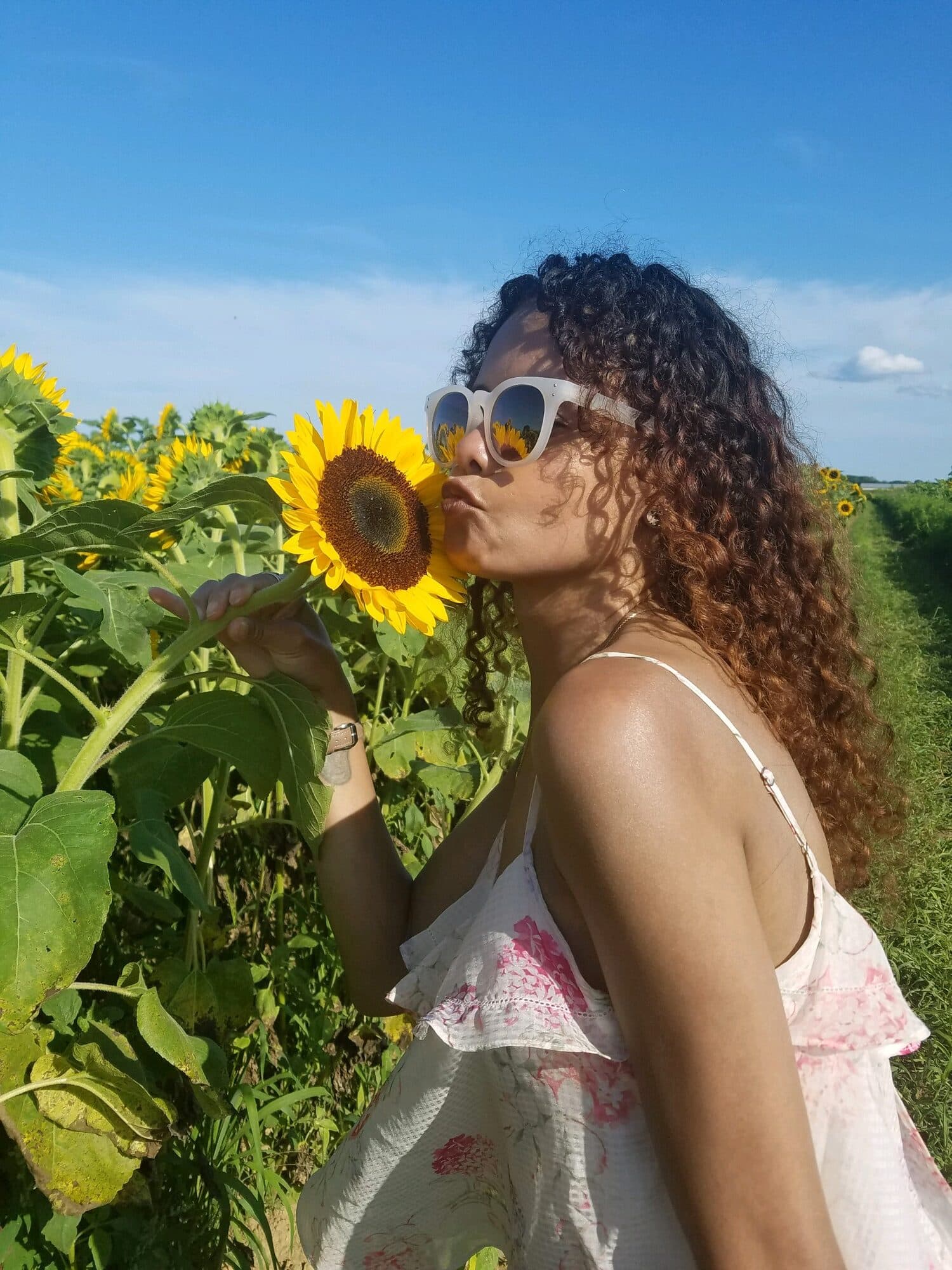 Amorette in a sunflower field, leaning in to kiss one of the blooms